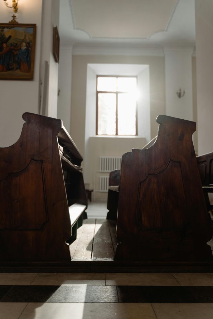empty church pews with lighting shining through a window